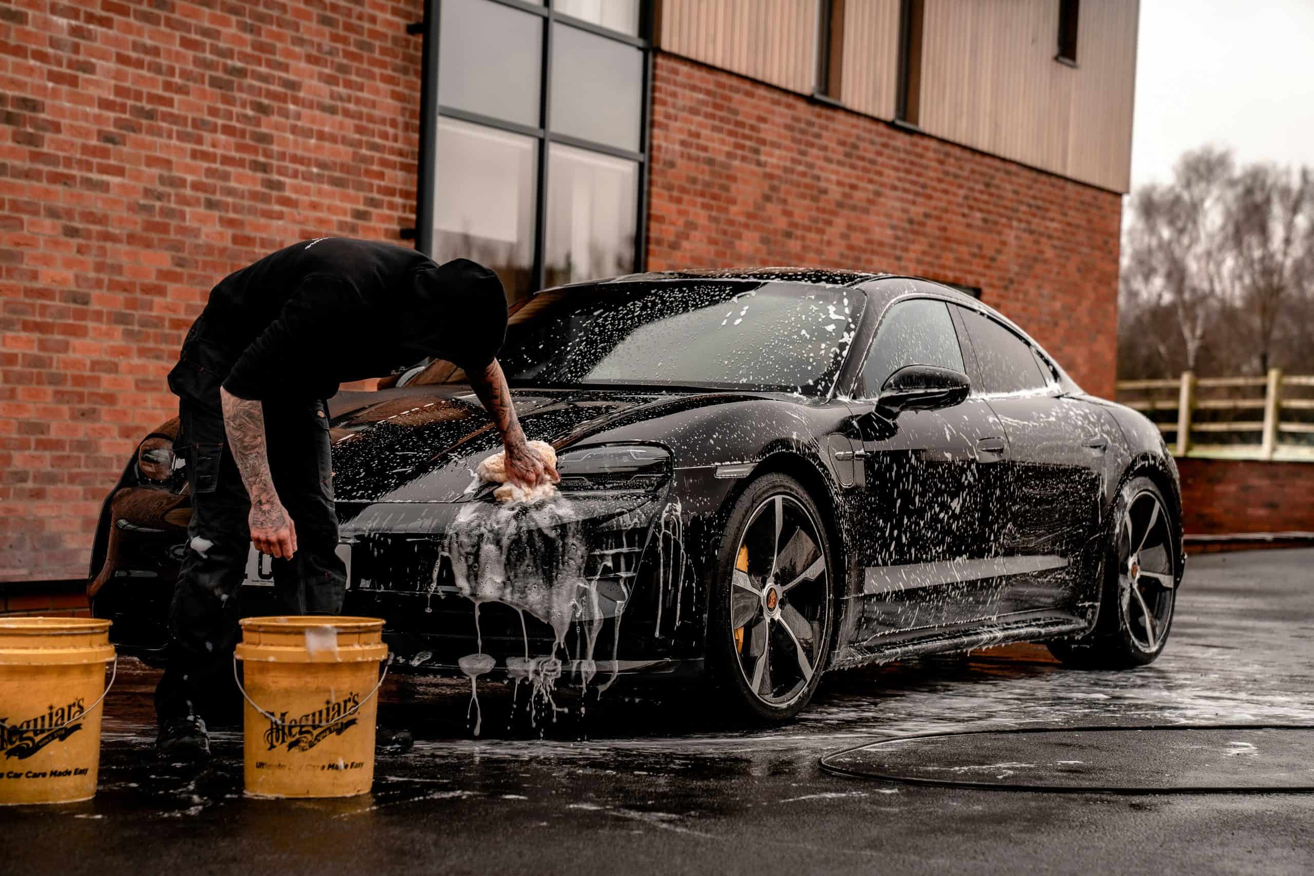 A man washing a black sports car